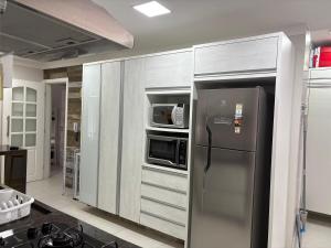 a kitchen with a stainless steel refrigerator and a microwave at Apartamento completo, 200mts da praia de Pitangueiras in Guarujá