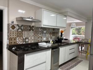 a kitchen with white cabinets and a stove top oven at Apartamento completo, 200mts da praia de Pitangueiras in Guarujá +14 photos