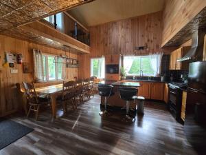 a kitchen with a wooden table and a dining room at Chalet COEUR de loup avec spa in Saint-Alexis-des-Monts