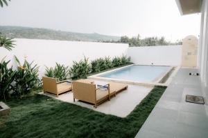 a backyard with a swimming pool and two chairs at Casa Verona in Lovina
