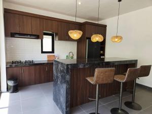 eine Küche mit einer Theke und 2 Hockern in der Unterkunft Hey-Sola Bali ,3BR Luxury Private Villa Near Canggu in Dalung