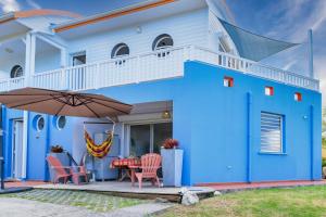 a blue house with a table and chairs and an umbrella at A L'Arche Bleue in Le Robert