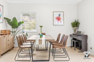Un comedor con una mesa y sillas y un piano. en KozyGuru | Erina | Sunny Coastal Escape + Parking, en Erina East
