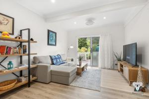 Una sala de estar con un sofá y un televisor. en KozyGuru | Erina | Sunny Coastal Escape + Parking, en Erina East
