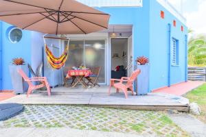 a blue house with a table and chairs and an umbrella at A L'Arche Bleue in Le Robert
