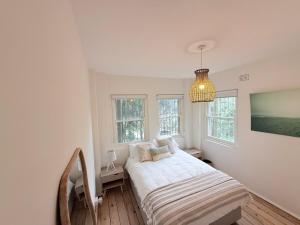 ein weißes Schlafzimmer mit einem Bett und einem Kronleuchter in der Unterkunft Bondi Palms in Sydney