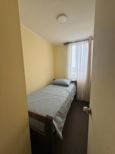 um pequeno quarto com uma cama e uma janela em Condominio Viña Oriente 2 em Viña del Mar
