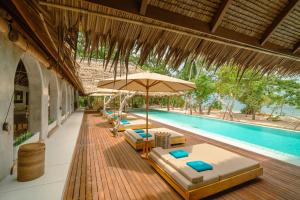 Coral Eye Boutique Resort and Marine Outpost في Likupang: مسبح خارجي مع كراسي للصالة ومظلة