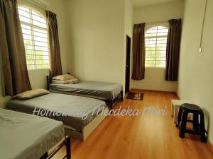 a bedroom with two beds and two windows at Homezstay Merdeka Miri in Miri