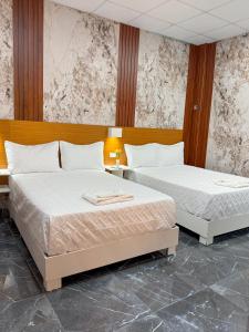 two beds in a hotel room with two bedsitures at Hotel baramar moca in Moca