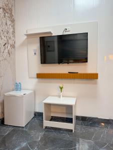 a white table with a tv on a wall at Hotel baramar moca in Moca +4 photos