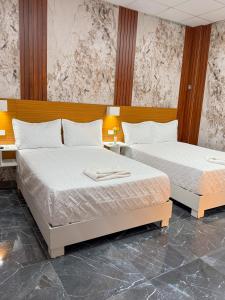 two beds in a room with two tables and two beds at Hotel baramar moca in Moca