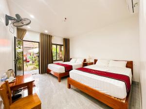 a bedroom with two beds and a desk and a window at Annamoi Homestay Tam Coc in Ninh Binh