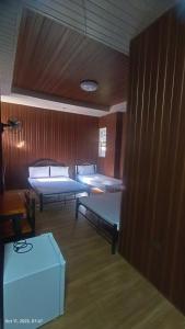 a room with three beds and a wooden wall at Kiyomi's Inn in Baguio