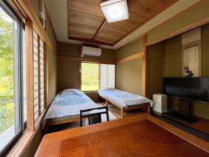 a room with two beds and a flat screen tv at Minshuku Ryokan Kawai in Shinshiro