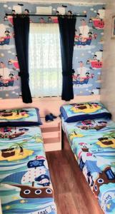 a bedroom with two beds with hello kitty and cars wallpaper at Ref G The Chase Caravan Park 3 bed 8 berth in Ingoldmells
