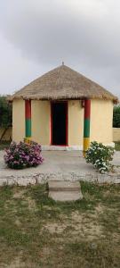 a small building with a thatched roof and a door at Rann Roshni homestay in Bherandiāla