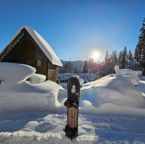 a snowboard sitting in the snow next to a cabin at Butter Hotel in Otari