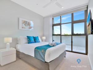 Un dormitorio blanco con una cama grande con almohadas azules. en CODA 410, en Coffs Harbour