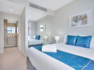 Un dormitorio con una cama grande con almohadas azules. en CODA 410, en Coffs Harbour 18 fotos más