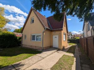 a small yellow house with a white garage at Holiday home in Zamardi - Balaton 53551 in Zamárdi