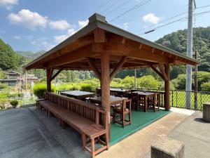 a wooden pavilion with wooden tables and benches at Minshuku Ryokan Kawai in Shinshiro