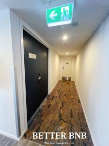 een gang met een zwarte deur en een bord aan het plafond bij Free Parking AC Cooling and CBD View in Wellington