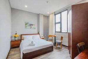 a bedroom with a bed and a table and a window at Silana River Light Hotel in Da Nang