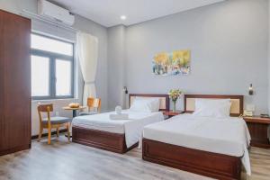 a bedroom with two beds and a desk and a window at Silana River Light Hotel in Da Nang