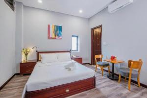 a bedroom with a bed and a table and a chair at Silana River Light Hotel in Danang