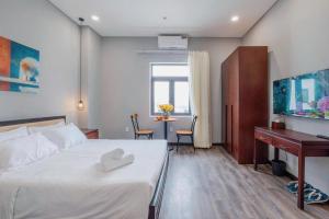 a bedroom with a bed and a desk and a table at Silana River Light Hotel in Danang
