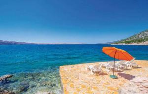 un gruppo di sedie e un ombrellone in spiaggia di Apartments Karlobag - Velebit Riviera 34630 a Karlobag (Carlopago)