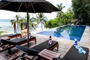 un complejo con piscina con sillas y sombrilla en viri Home, en Panglao