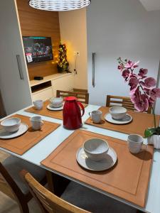 a dining room table with plates and bowls on it at Apartamento quarto e sala, varanda com vista para a Pedra Azul e cozinha completa no Condomínio Vista Azul in Pedra Azul