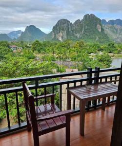 een houten tafel en bank op een balkon met bergen bij west water hostel in Vang Vieng +15 foto's