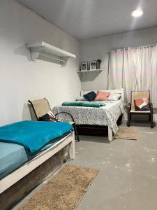 a bedroom with two beds and a chair in it at Chalé Praia Doce in Belém