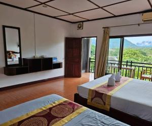 een hotelkamer met twee bedden en een balkon bij west water hostel in Vang Vieng