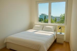 a white bed in a room with two windows at Modern Apartment with Balcony near Vienna in Wiener Neudorf