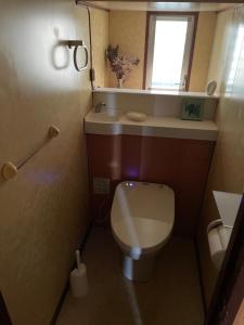a small bathroom with a toilet and a window at kumanonisumu! in Kumano