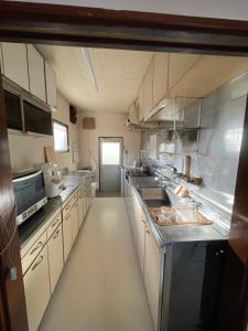 a large kitchen with white cabinets and a sink at kumanonisumu! in Kumano +4 photos