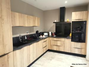 a kitchen with wooden cabinets and a black appliances at Gîte HUGO Domaine de la Pierre - FR-1-489-339 in Thiel-sur-Acolin +8 photos