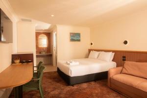 a bedroom with a bed and a couch and a table at The Alluna Motel, an Ascend Collection Hotel in Armidale