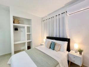 a white bedroom with a bed and a window at Rich Villa Guesthouse in Bayamon