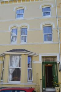 a yellow house with a red car parked in front of it at Sea Breeze Guest House in Douglas