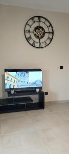 a large clock on the wall above a television at Hedeun studio in Fort-de-France