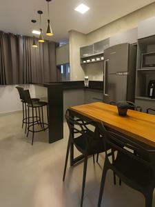 a kitchen with a wooden table and black chairs at SQ131A Moderno e Aconchegante in Goiânia