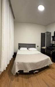 a bedroom with a large bed with white sheets at 1Kitnet ao lado da Praça Leonardo Venerando in Lavras