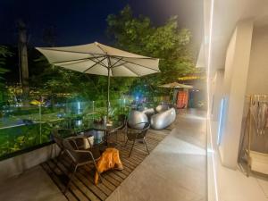 een terras met een tafel, stoelen en een parasol bij Phoenix Mountain View Courtyard Homestay in Fenghuang