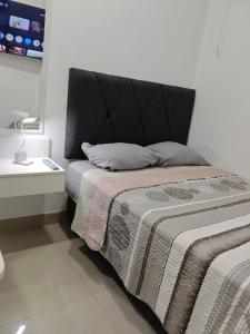 a bed with a black headboard in a room at Habitacion con entrada independiente y aire acondicionado, Centro Piura in Piura
