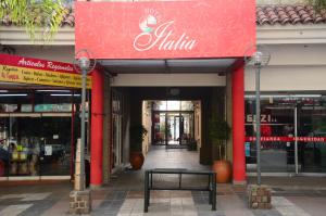 un banco frente a una tienda con una señal roja en Hotel Italia en Villa Carlos Paz